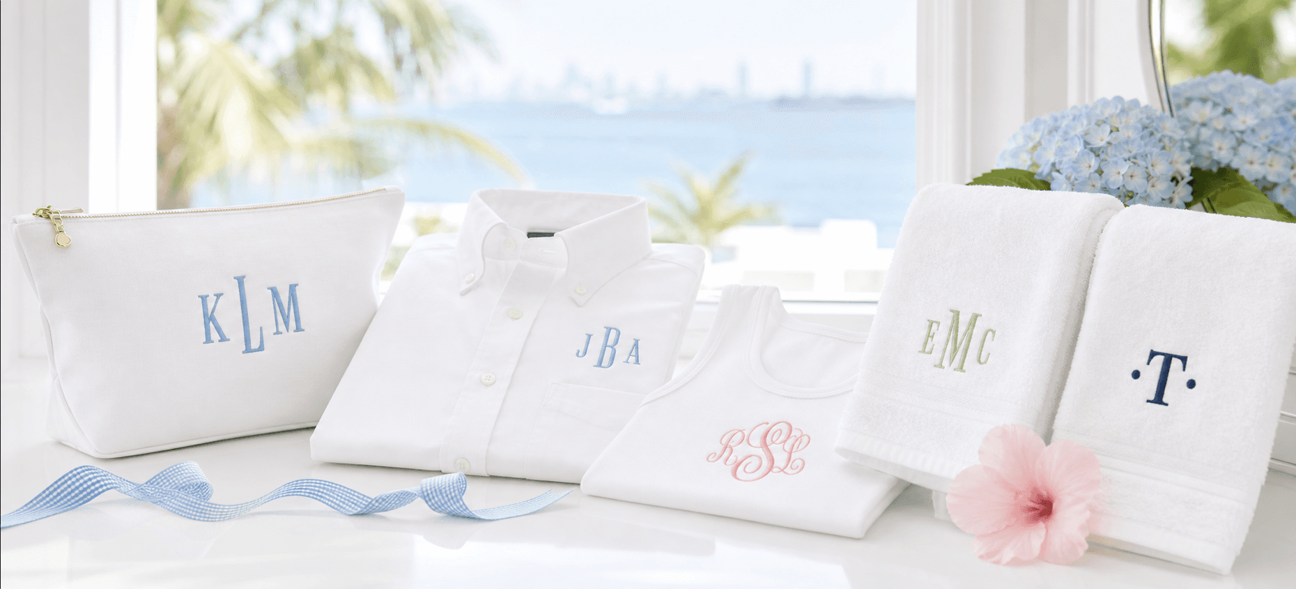 Custom embroidered toiletry bag, button down, tank, and towels styled by a sunny Miami window